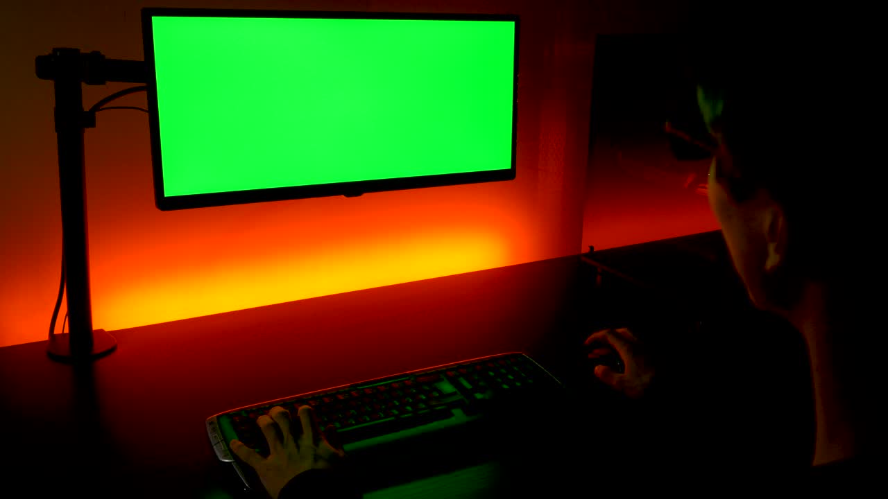 pantalla verde: toma sobre el hombro de un hombre caucásico escribiendo en el teclado frente al monitor