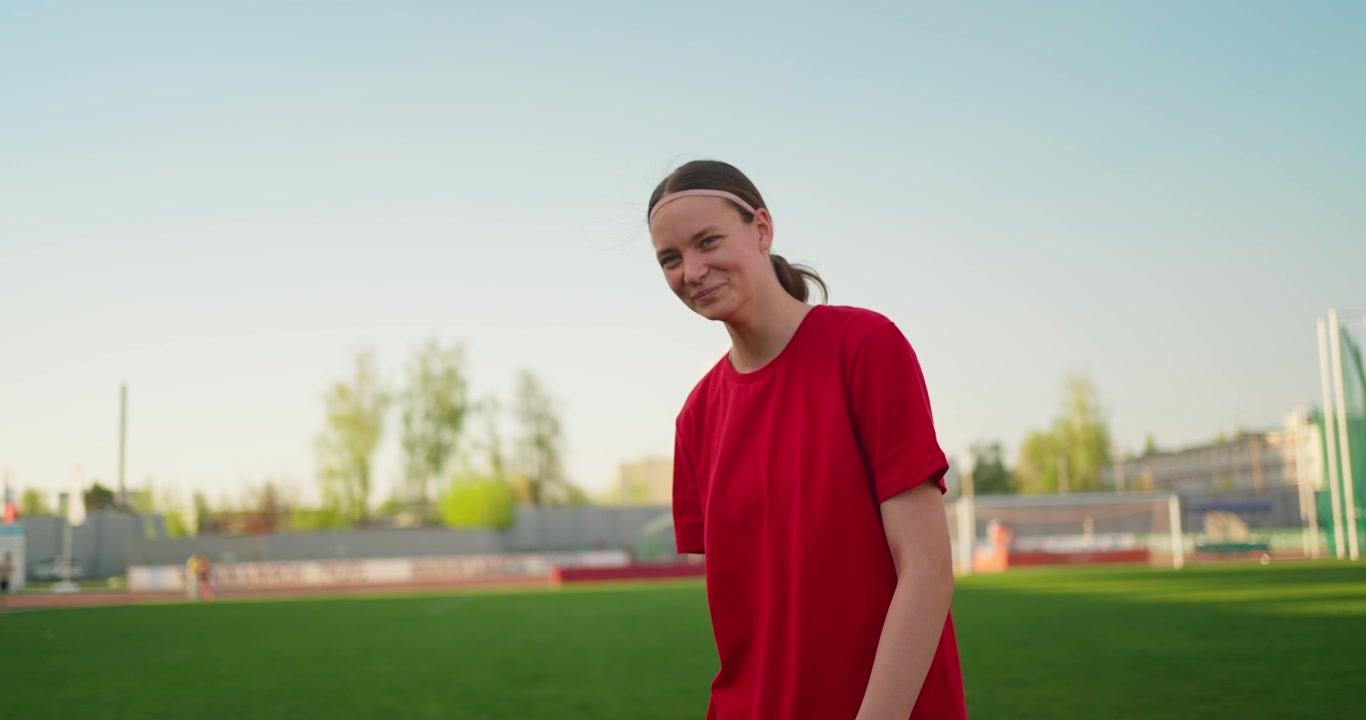 Jovem Atleta Sorridente em Pé em um Campo Esportivo Verde