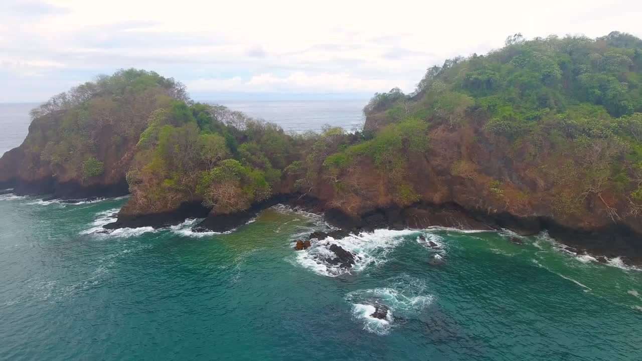 Sliding out along a peninsula on Tortuga Island in Costa Rica with an aerial view of the calm water hitting the shore