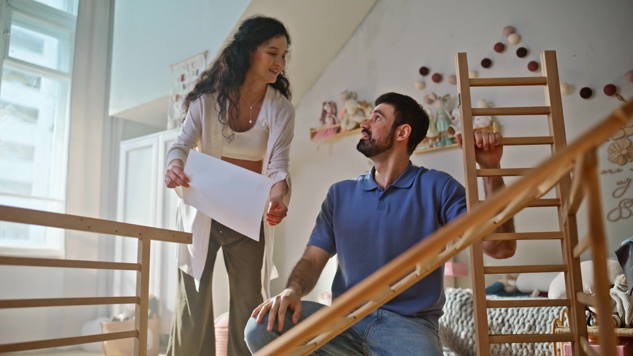 Futuros pais montando berço no quarto do bebê. Esposa grávida e marido em casa.