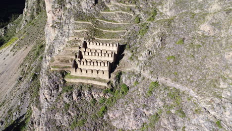 Drone-establishing-view-of-historic-town-site-of-Ollantaytambo-cut-out-of-hillside-in-Peru