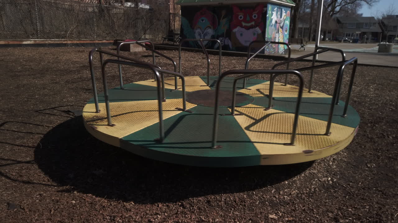 A kid's Merry Go Round spinning in a community park, wide shot