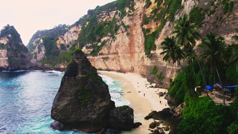 Sandy-Diamond-beach-with-sea-waves-and-vacationing-people-below-cliff