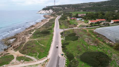 Disparo-De-Un-Dron-Tras-Un-Coche-De-Golf-Conduciendo-Por-Una-Carretera,-Filmado-En-Rosh-Hanikra,-Israel