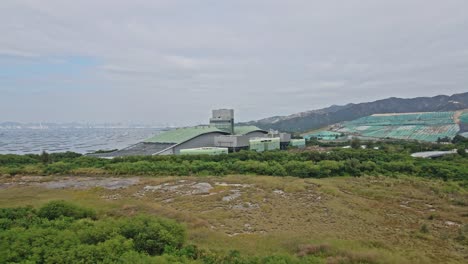 Drone-flying-towards-T-Park-Sludge-Treatment-Centre-in-Tuen-Mun-Tsang-Tsui,-Hong-Kong