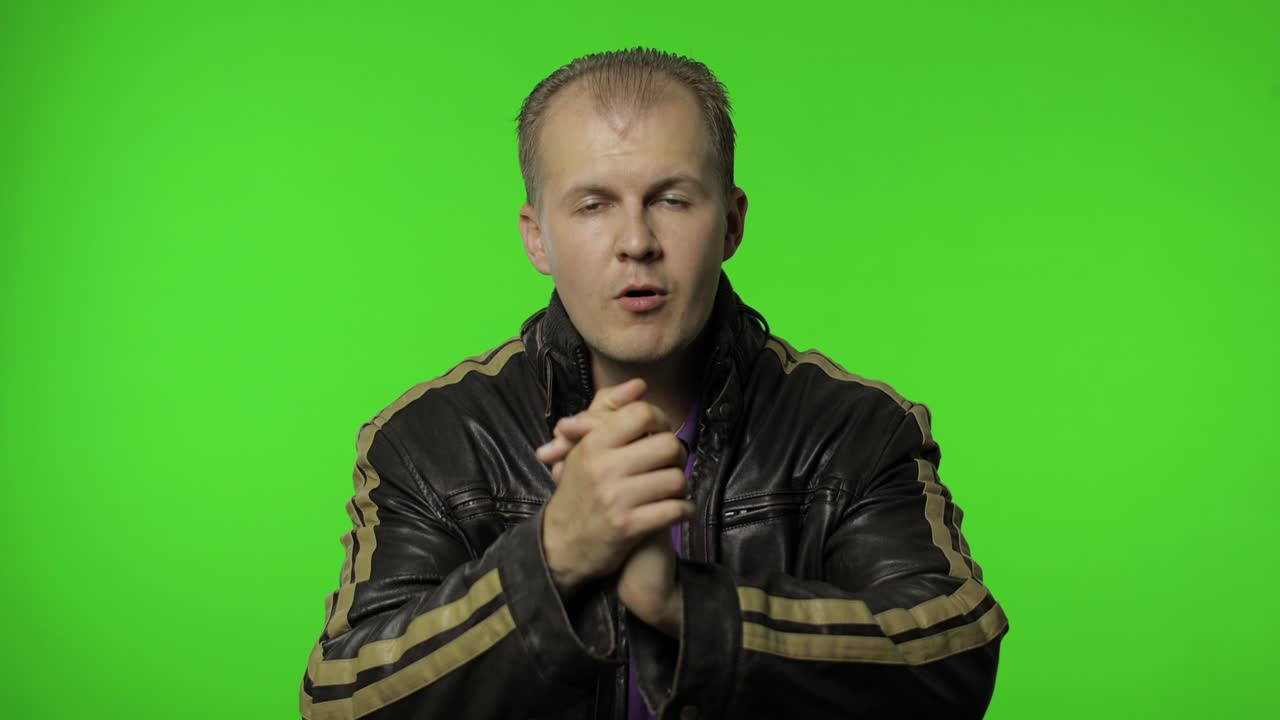 갈색 제임스 재을 입은 행복한 로커 남자가 손을 치고 자랑스러운 표정으로 바라보고 있습니다.