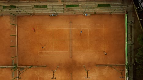 birds-eye-view shot of a doubles match of tennis being played on a clay court in mendoza