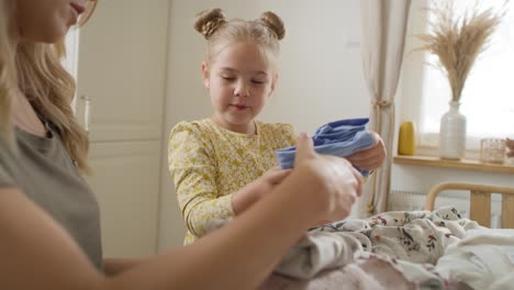 Tracking-video-of-daughter-and-mother-sorting-clothes-for-donation