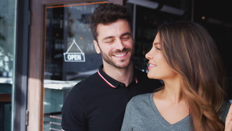 retrato de una pareja propietaria de una cafetería o restaurante de pie en la puerta