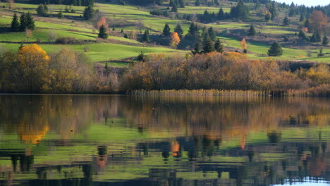 golden foliage reflects on the calm lake water