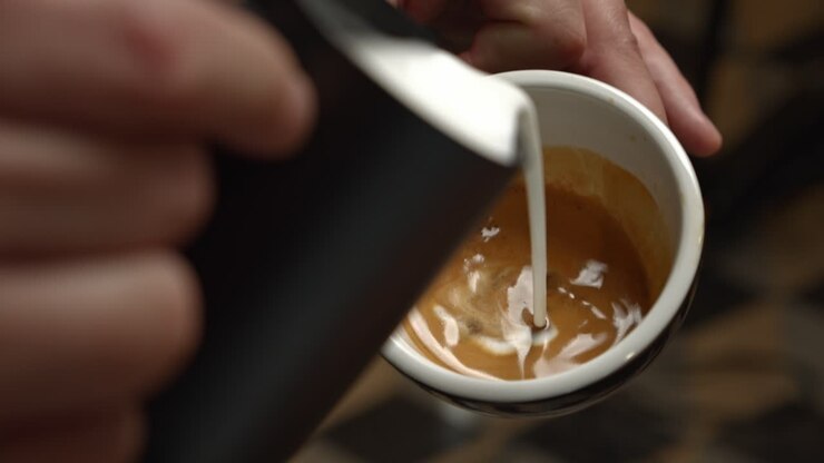 Un barista serve un cappuccino decorato con Latte Art