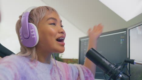 woman gaming at home sitting at desk wearing headphones for live stream