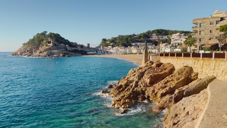 Bahía-De-Tossa-De-Mar-Vista-Desde-El-Castillo-Hasta-La-Playa-Con-Arena-Gruesa-Y-Agua-De-Mar-Azul-Turquesa-Antiguo-Pueblo-Pesquero-Medieval-Amurallado-Mar-Mediterráneo