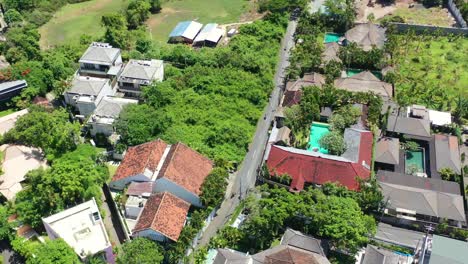 Antena-De-Arriba-Hacia-Abajo-De-Scooters-Que-Conducen-A-Través-De-Un-Barrio-Rural-En-Una-Isla-Tropical