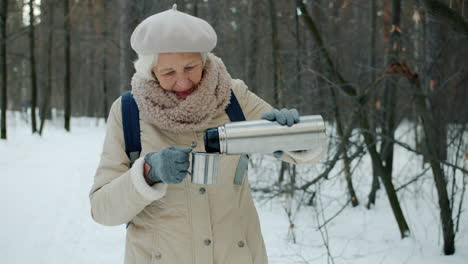Senior Woman Hiking and Drinking Hot Tea in Winter Forest