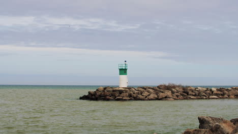 Water-moving-in-slow-motion-by-small-green-and-white-lighthouse