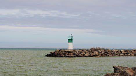 agua moviéndose a cámara lenta por un pequeño faro verde y blanco