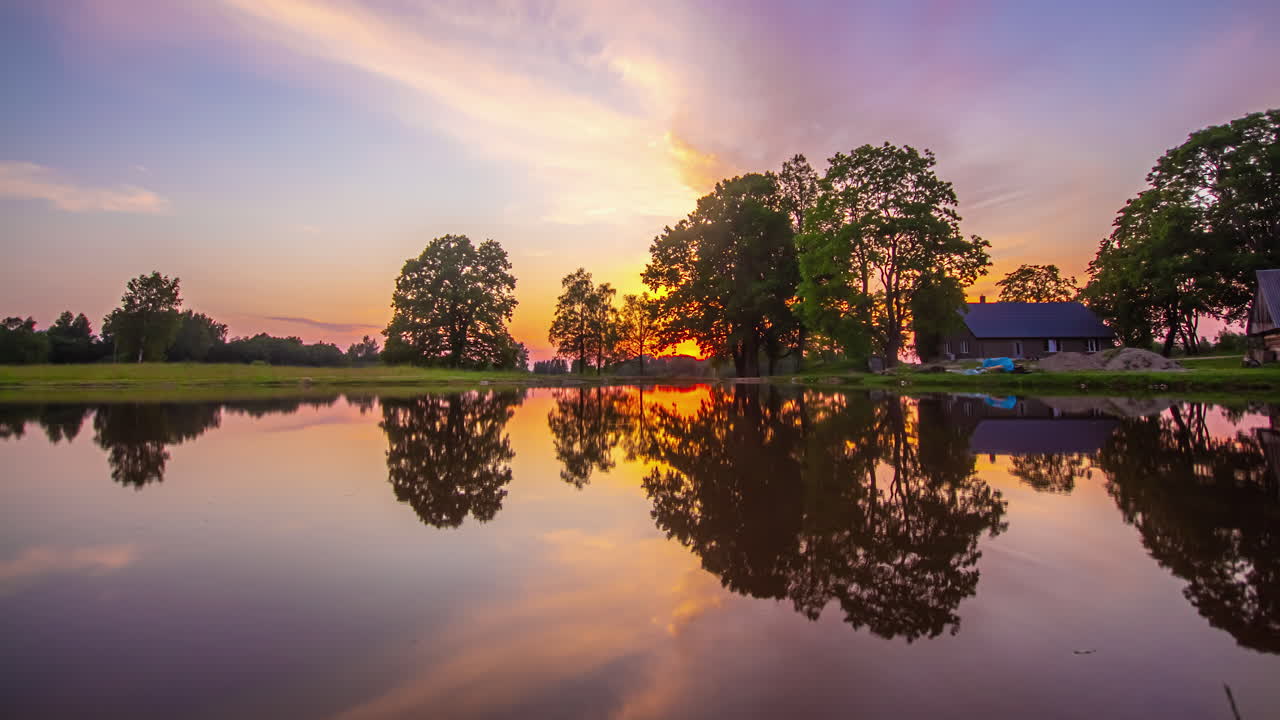 해안에 오두막이 있는 호수에서 반사되는 황금빛 일몰 - 시간 경과