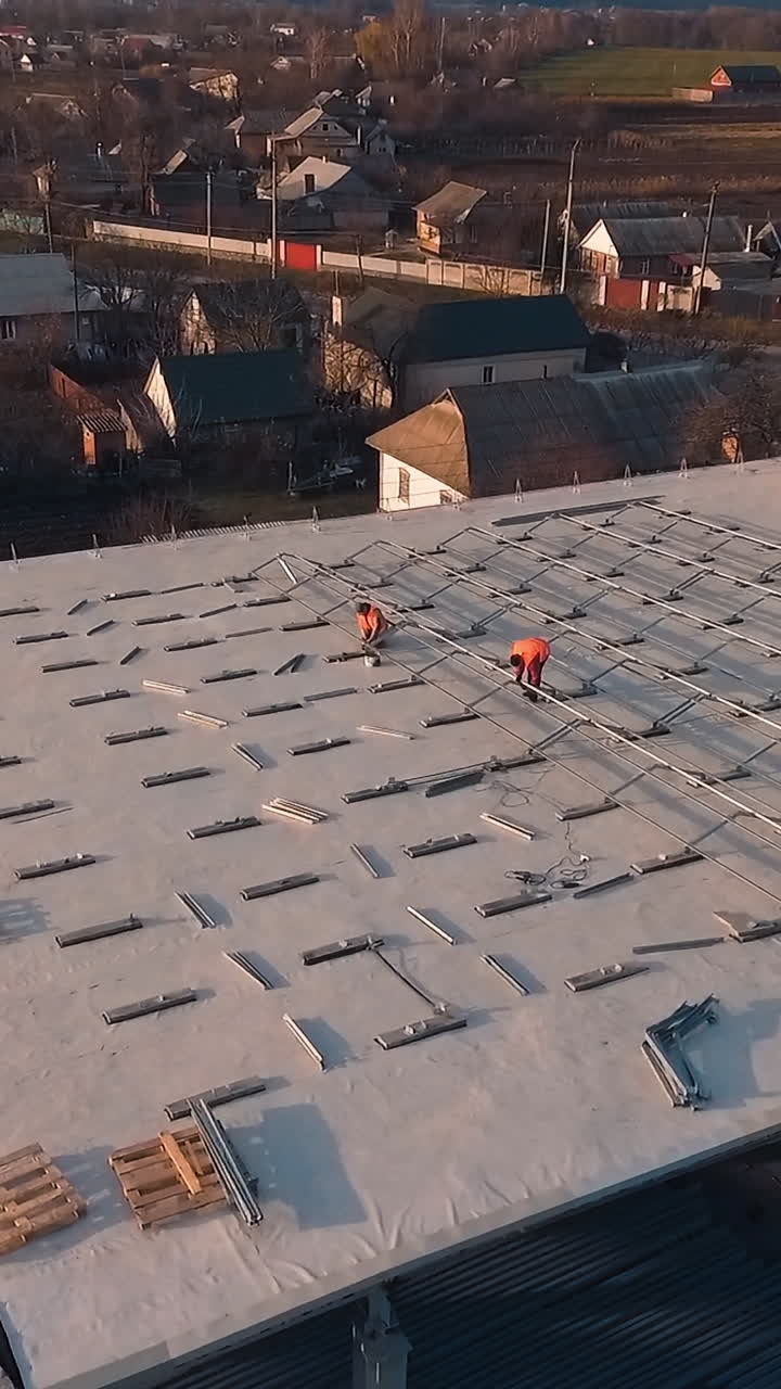 Workers on roof installing solar panels. Electricians working to install solar panels on roof of building