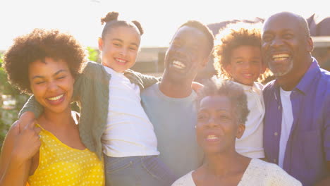 Porträt-Einer-Familie-Mit-Mehreren-Generationen-Draußen-Im-Heimischen-Garten-Vor-Der-Gleißenden-Sonne