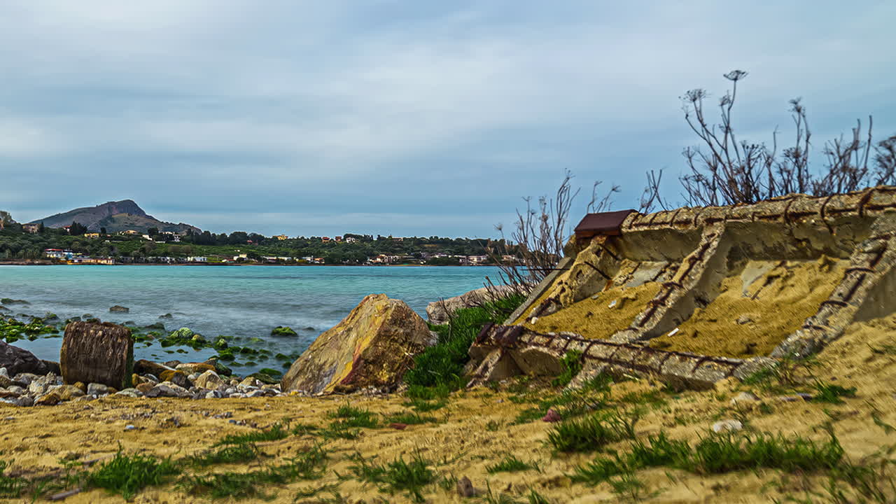 철근 콘크리트의 잔해가 해안의 바위 해변에 폐허로 놓여 있습니다.