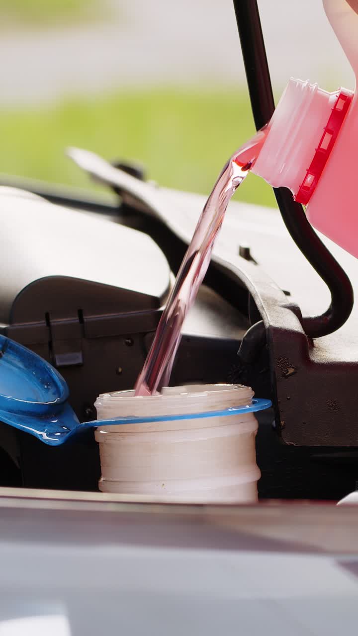 서비스 직원 남자는 자동차 유체 앞유리 빨간색 청소 세탁기 유리 여름 또는 겨울 청소기를 붓습니다