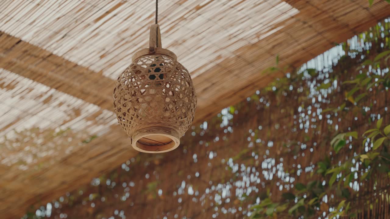 자연광 아래 야외에 걸려 있는 장식적인 등나무 램프