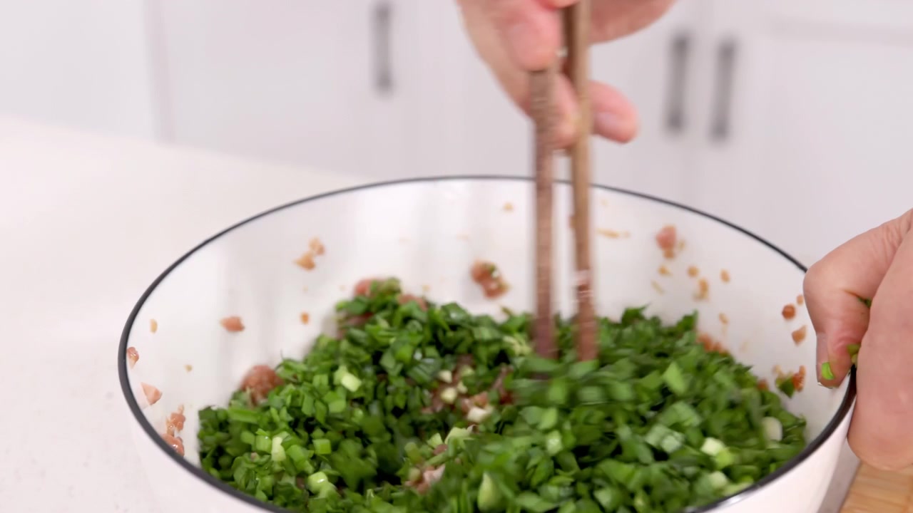 Uidentificerede hænder af en ældre kvindelig bagerkok, der laver velsmagende hjemmelavede fyldte dumplings, proces med at røre hakket kød og grøntsager i en skål på et hjemmekøkkenbord. Koncept: hjemmelavet mad, sund mad.