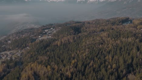 Wide-aerial-reveal-of-Alpine-panorama-in-Swiss-Alps-with-mountain-towns-and-lush-pine-forests