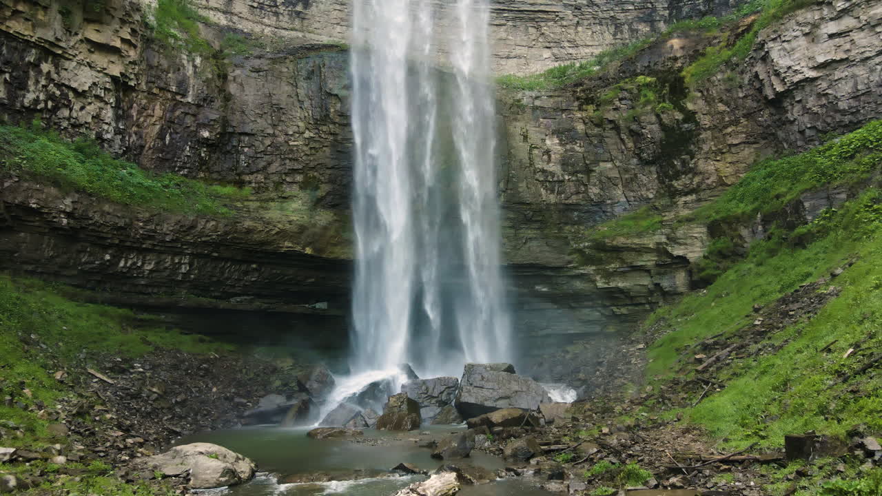 Inquadratura all'indietro dalla base delle cascate di Tew con acqua che cade spruzzando vapore mentre colpisce le rocce.