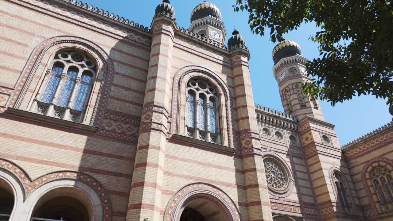 Dohány Street Synagogue in Budapest, featuring detailed arches, towers, and decorative facade, with trees framing the historic landmark