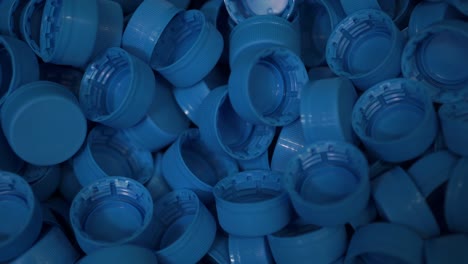 piles of blue plastic caps lie in a box at a drinking water bottling plant