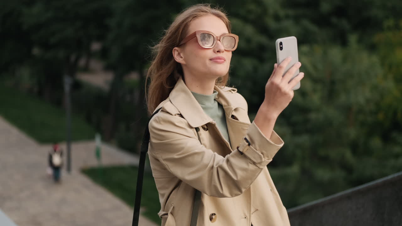 백인 여성 학생이 야외에서 셀카를 찍고 있습니다.