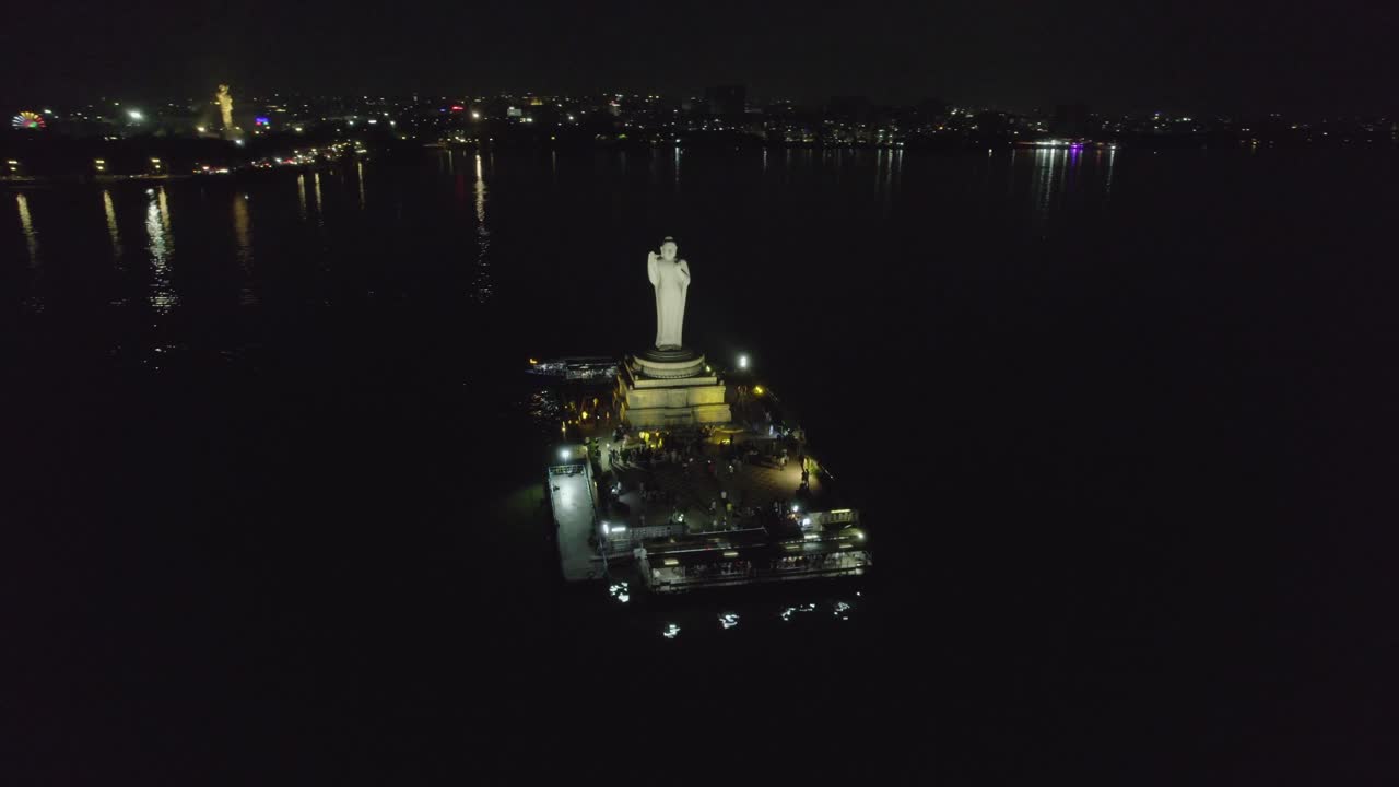 A cinematic aerial shot of Hussain Sagar Lake, Hyderabad's most well-known landmark, at night Indian monolith known as the Buddha Statue of Hyderabad