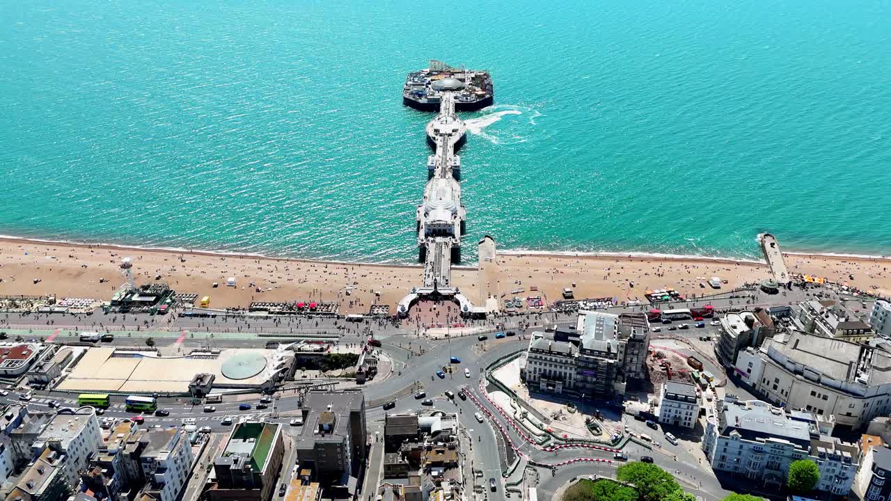 Sunlit serenity meets coastal energy. A high-flying look at Brighton’s bustling beach, boats circling the pier, and the sea glistening in the warm glow of summer.