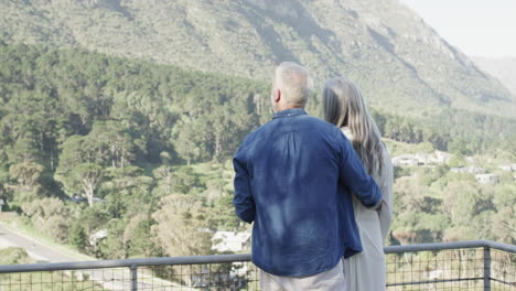 Feliz-Pareja-Caucásica-De-Mediana-Edad-Hablando-Y-Abrazándose-En-Una-Terraza-En-Las-Montañas,-Cámara-Lenta