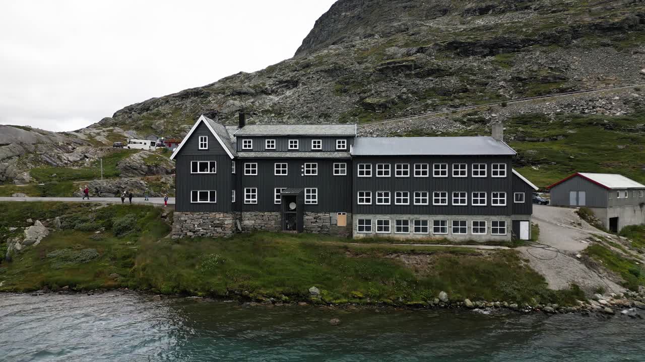 gran casa gris en un gran lago azul en las montañas, noruega, europa, dron