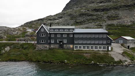 big grey house on a large blue lake in the mountains, norway, europe, drone