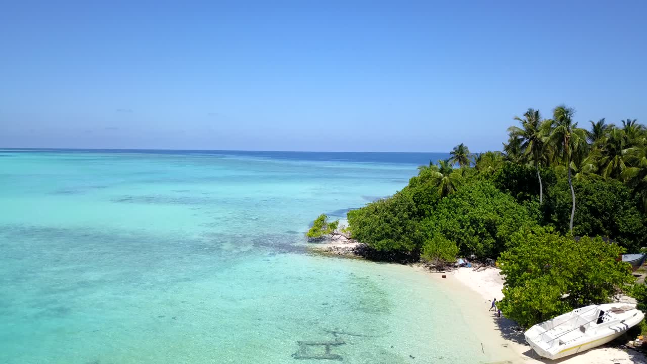 Due persone che camminano su un'isola deserta con una barca abbandonata e un magnifico oceano luminoso