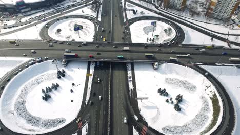 cars traffic on highway junction in winter city. aerial view freeway overpass