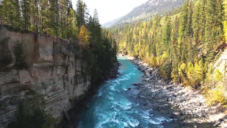 forward dolly in aerial zoom shot of rearguard falls drone flying down the river on a sunny day in autumn in a forest environment and the fraser river