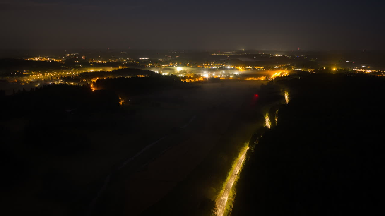 Aerial hyperlapse of night mist above a train and traffic in illuminated Espoo