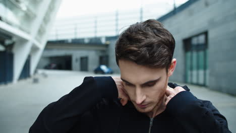 Portrait-of-handsome-man-walking-street.-Close-up-focused-guy-correcting-hood