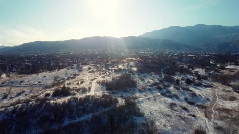 Aerial-pull-back-from-sunny-winter-mountains-and-snowy-roads-in-Colorado