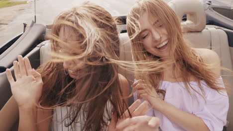 two happy friends enjoying a road trip in a convertible