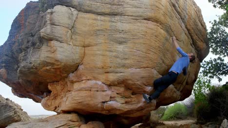 excursionista masculino escalando una montaña rocosa en el campo 4k