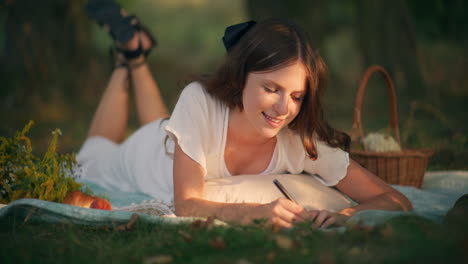 smiling girl writing dreams on picnic blanket
