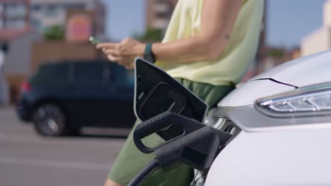mujer cargando un coche eléctrico con un teléfono inteligente