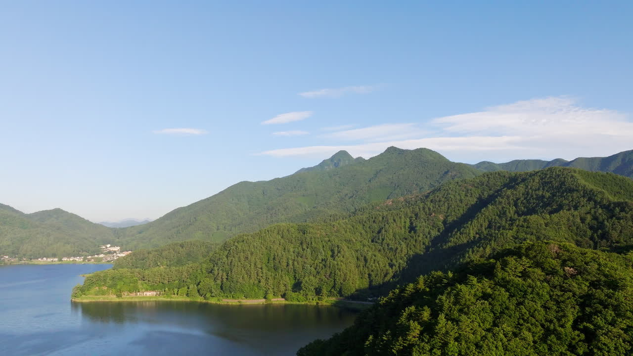 Drone shot of the mountainous coastline of lake Kawaguchi, sunny day in Japan