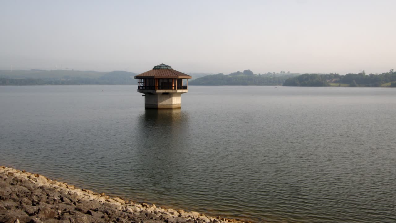 fotografía amplia de la torre de la válvula de agua de carsington, la torre de extracción y el camino de la presa